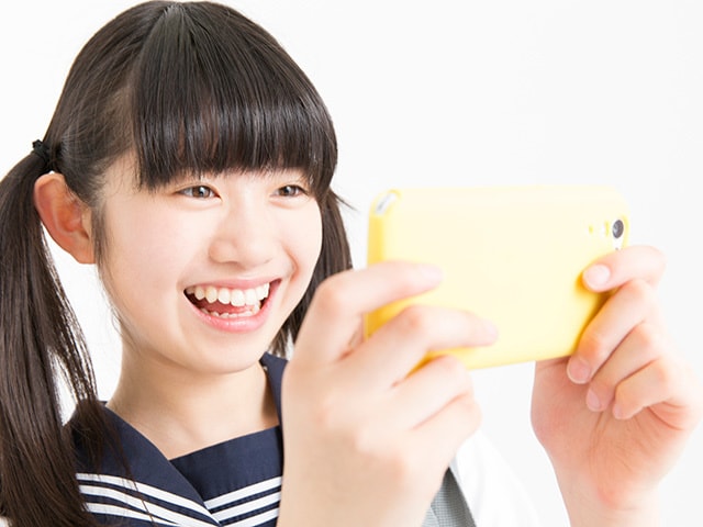 スマホで歌のオンラインレッスンを受講する女子学生